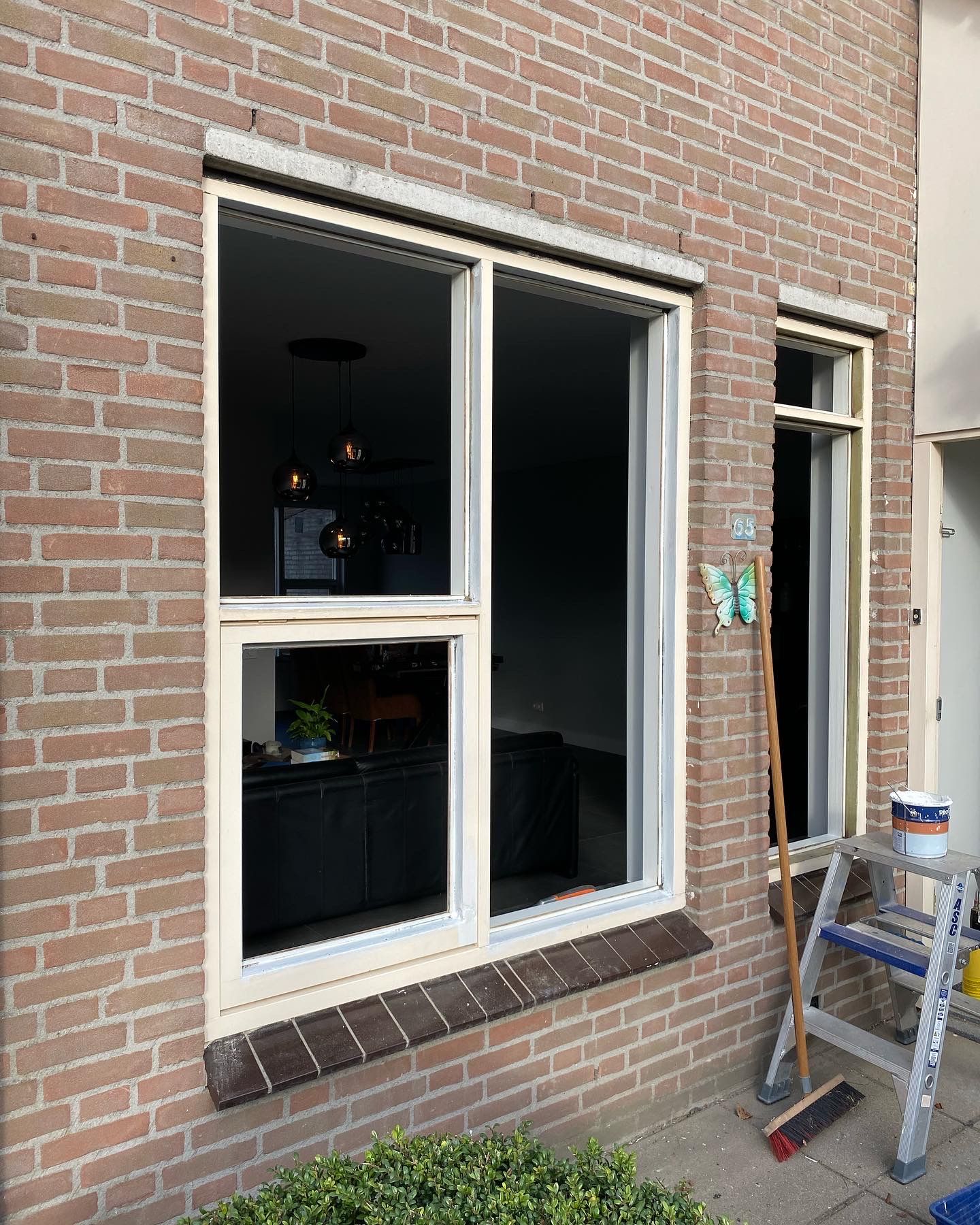 Een bakstenen gebouw met een raam en een ladder ervoor.