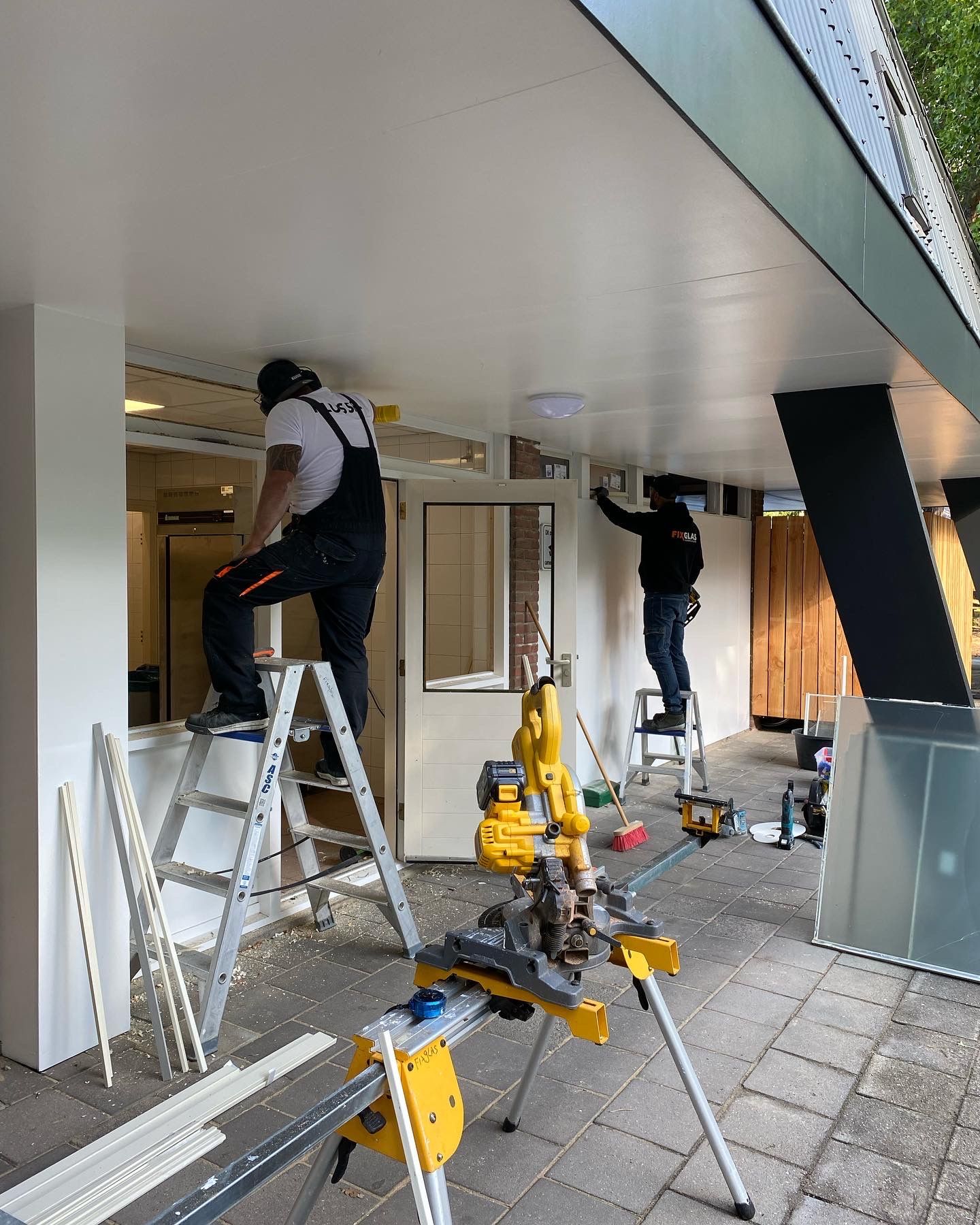 Twee mannen werken aan het plafond van een gebouw.