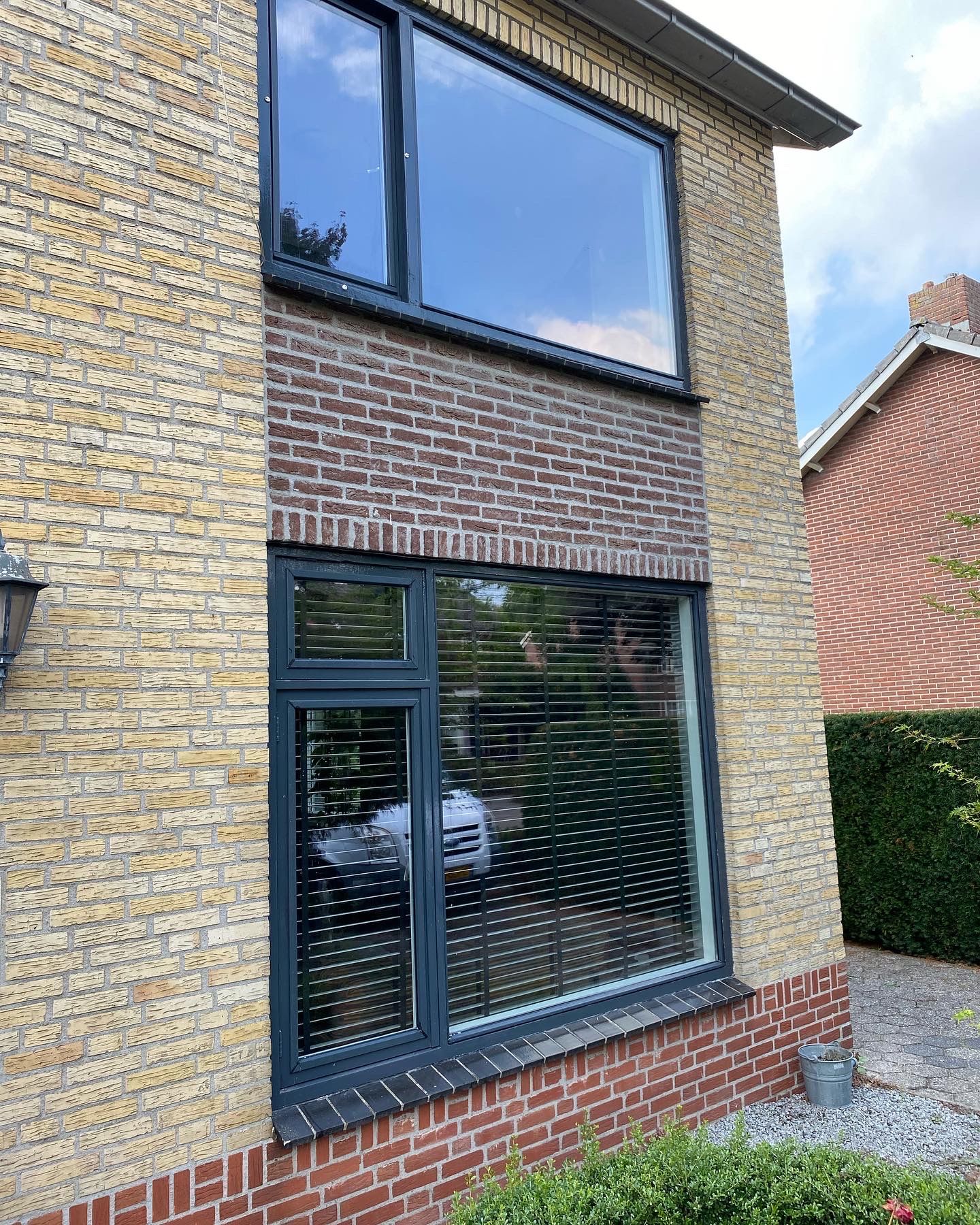 Een bakstenen huis met een groot raam aan de zijkant.