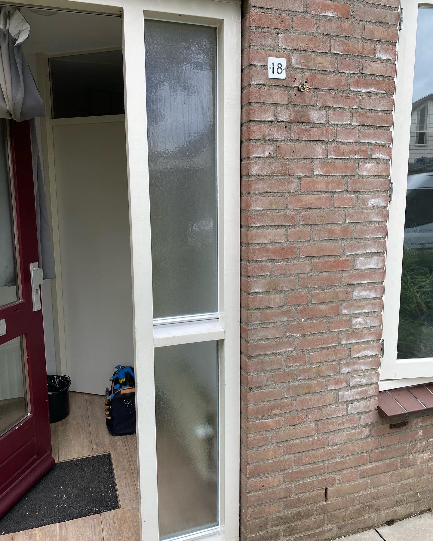 Een bakstenen gebouw met een rode deur en een witte deur