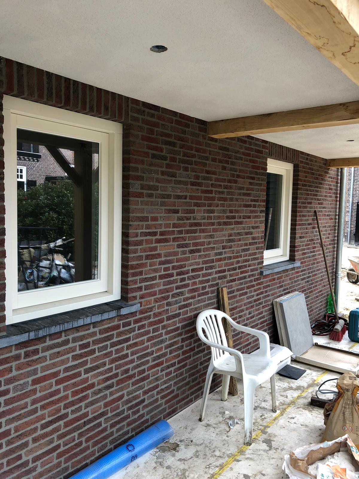 Een bakstenen muur met een witte stoel ervoor.