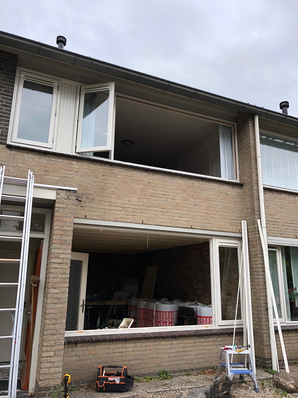 Een bakstenen huis met veel ramen en een ladder ervoor.