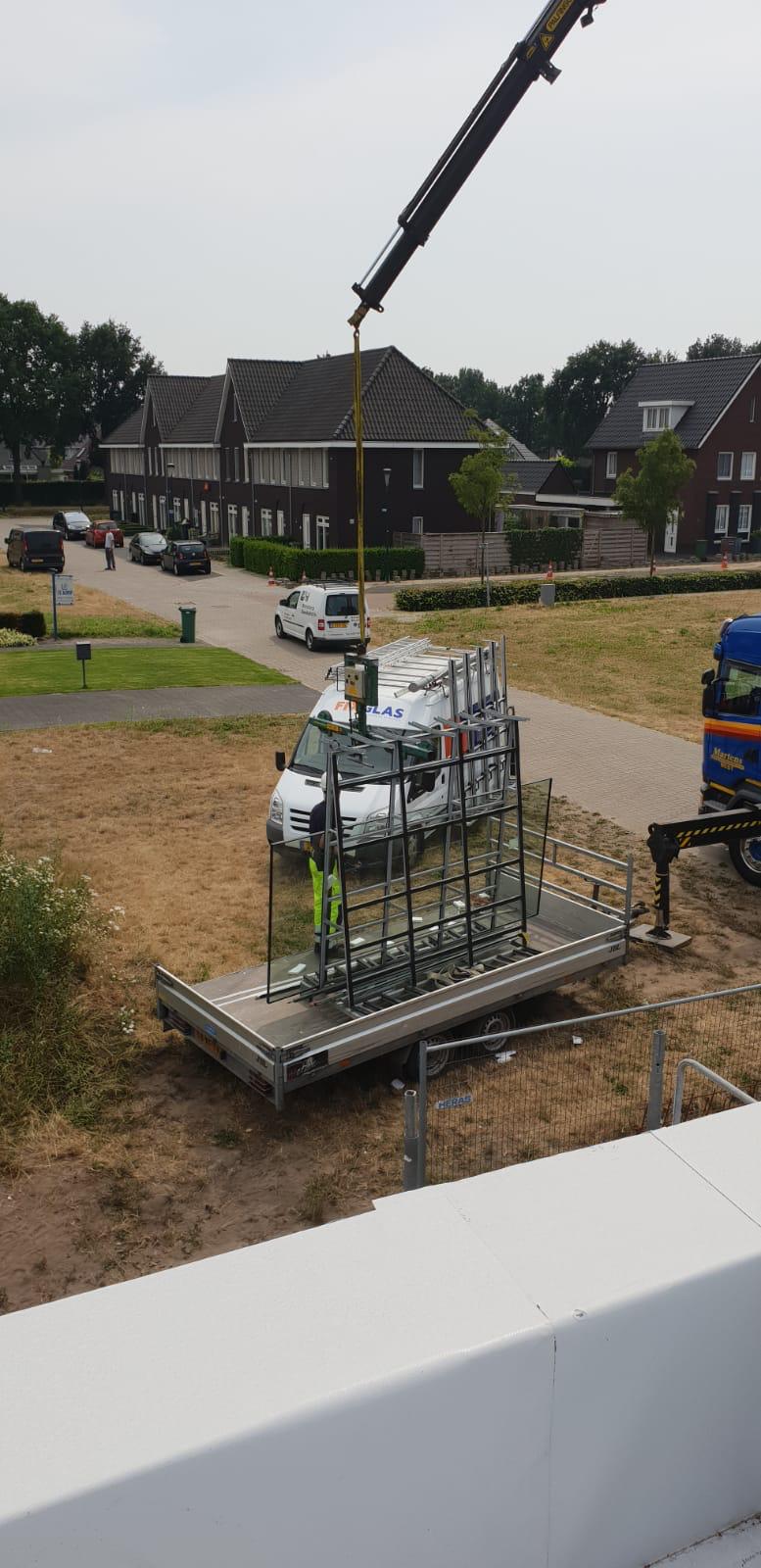 Een kraan tilt een bestelwagen op in een veld.