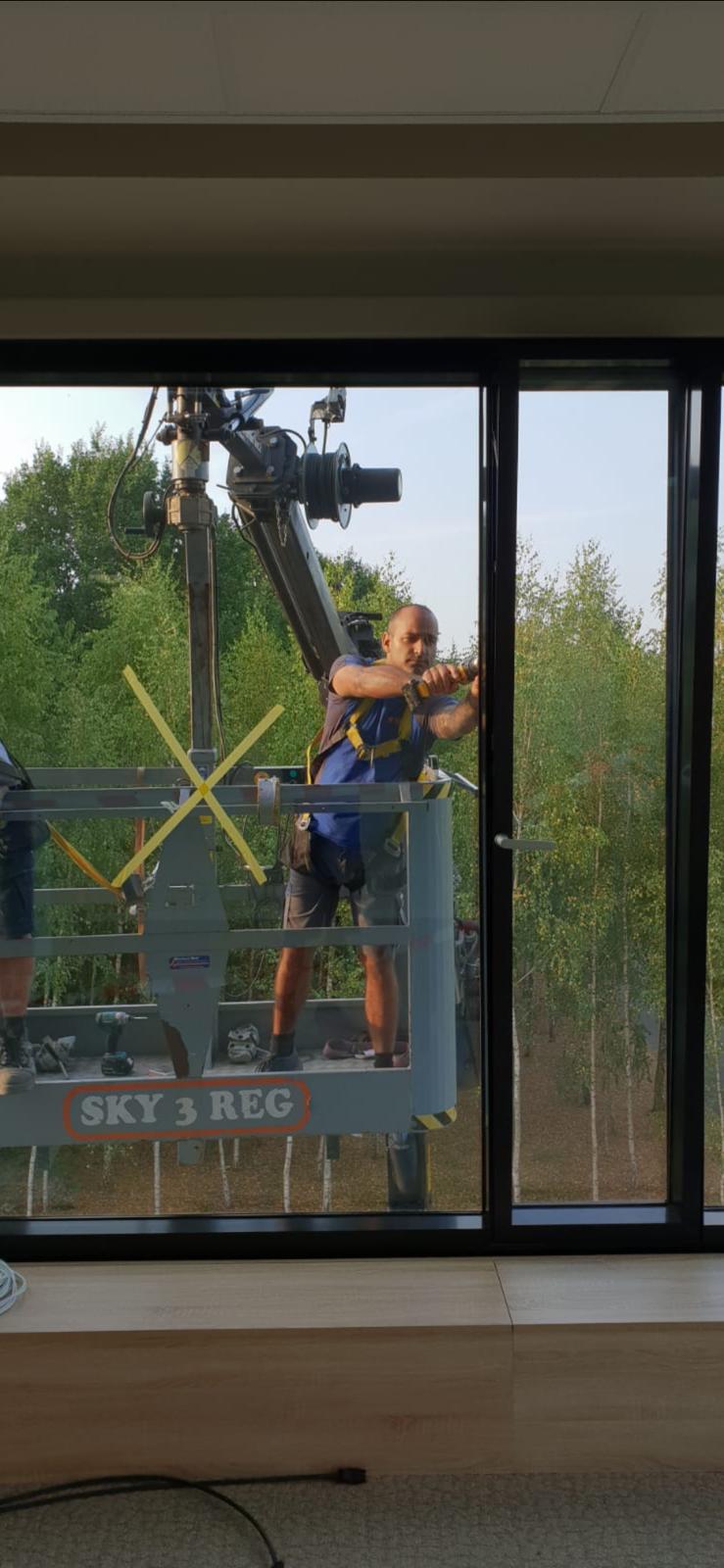 Een man maakt in een kamer een raam schoon met een machine.
