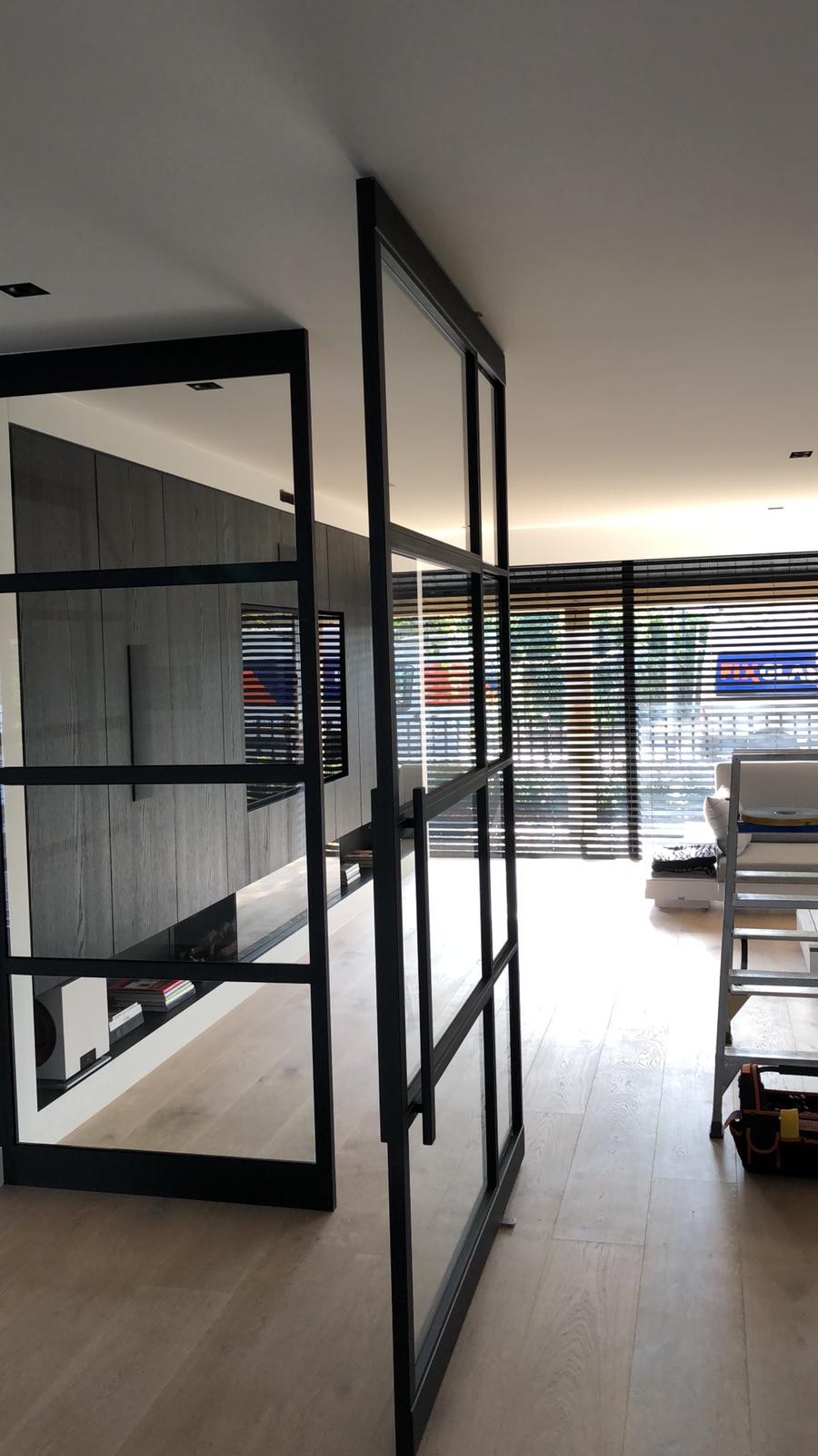 Een kamer met veel ramen en een zwarte deur