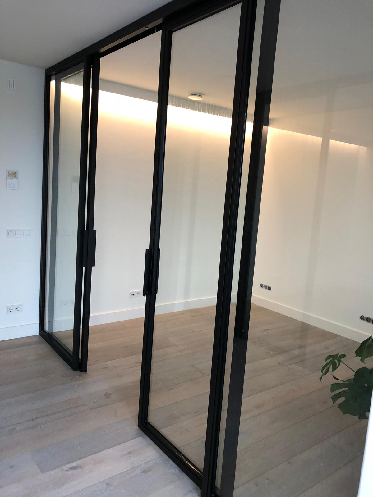 Een kamer met glazen schuifdeuren en een plant in de hoek.