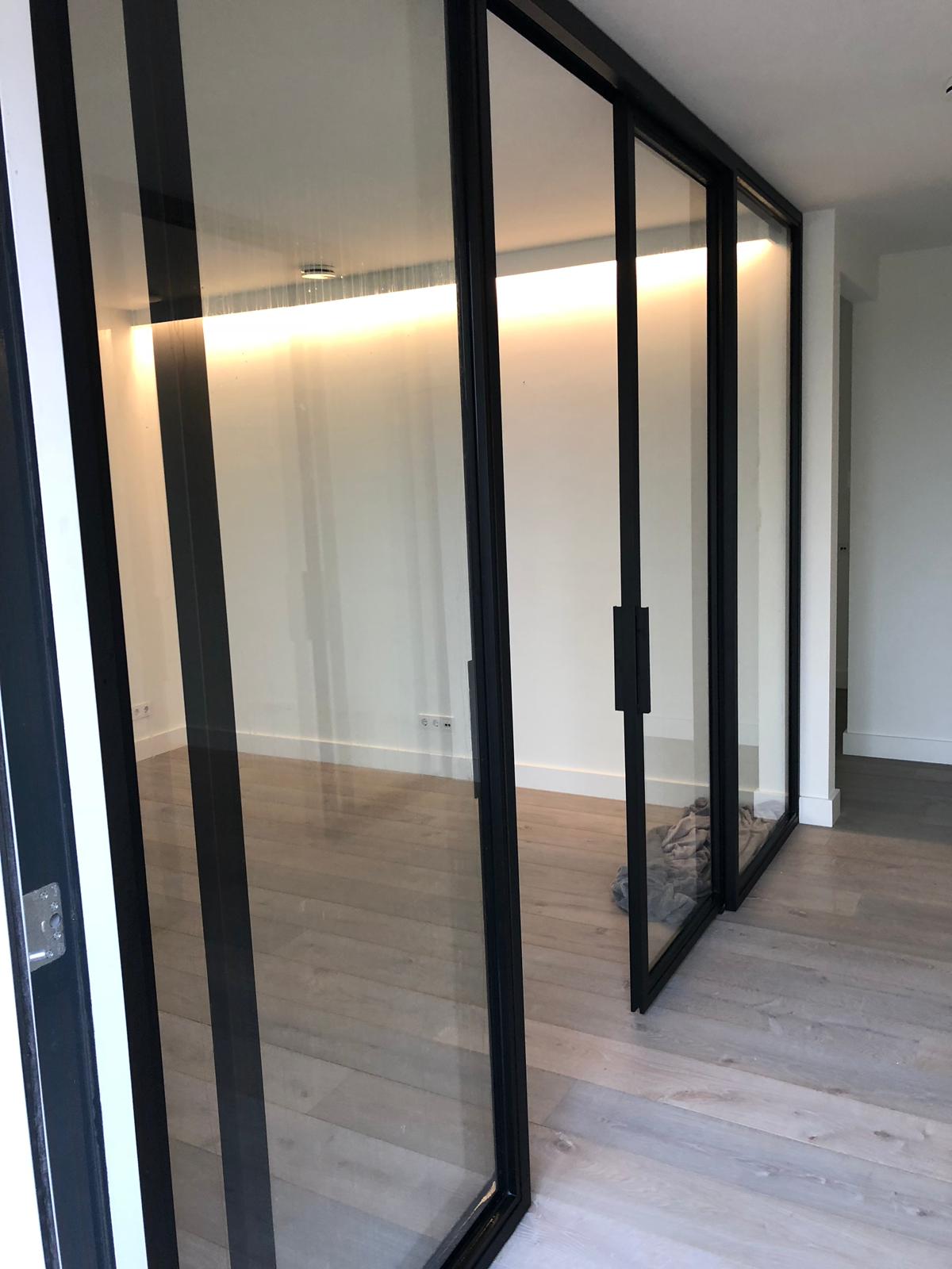 Een kamer met glazen schuifdeuren en een houten vloer