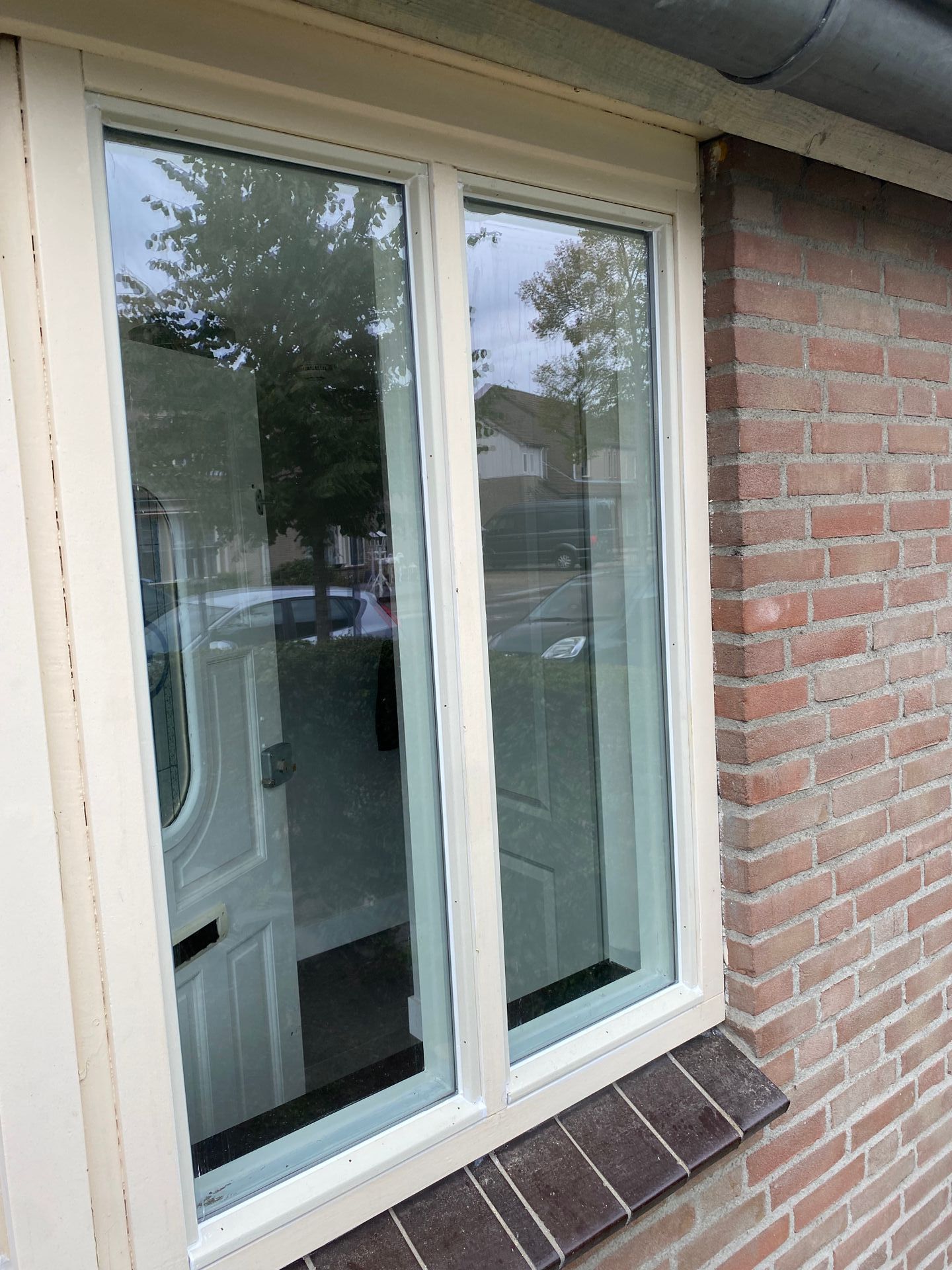 Een raam aan de zijkant van een bakstenen gebouw met een wit kozijn.