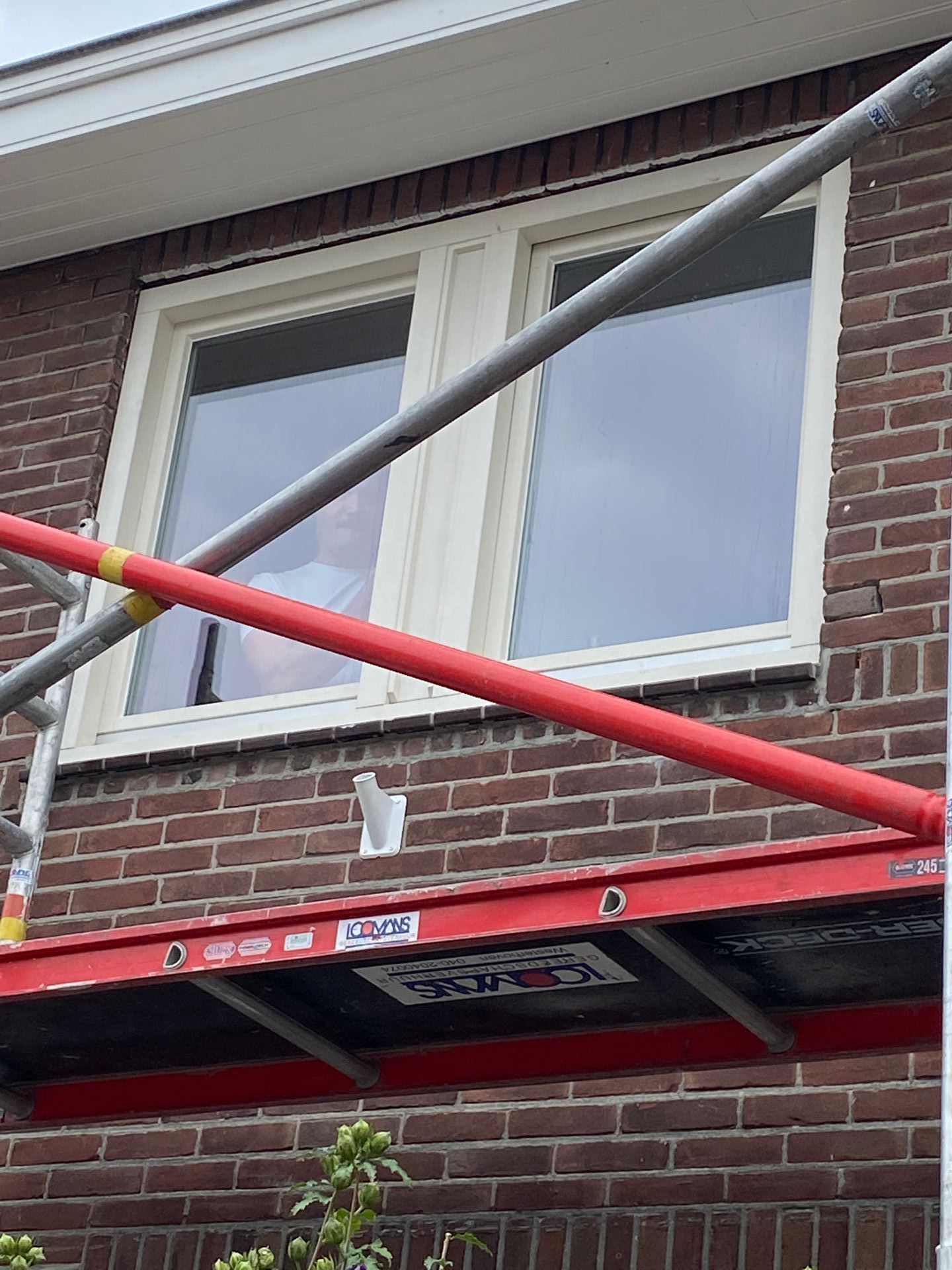 Een bakstenen gebouw met een raam en een steiger ervoor.