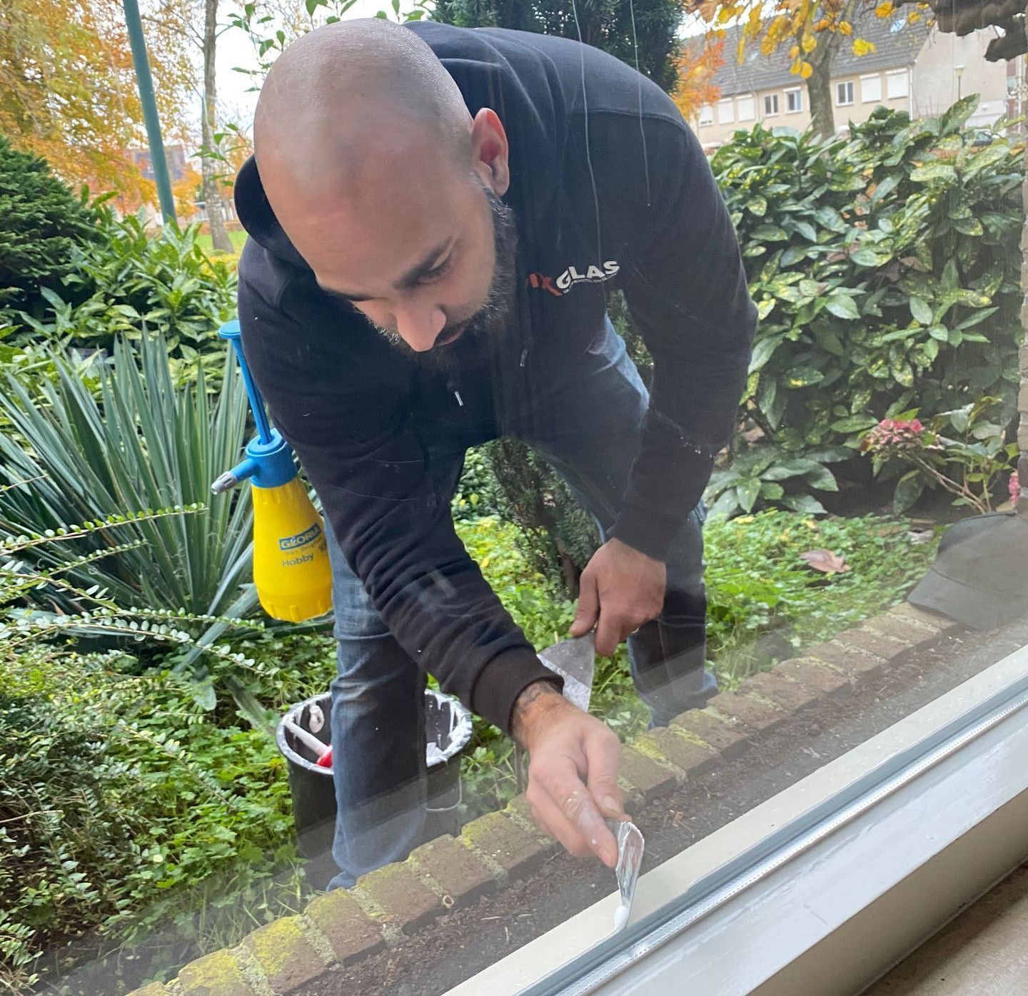 Een man maakt een raam schoon met een spatel