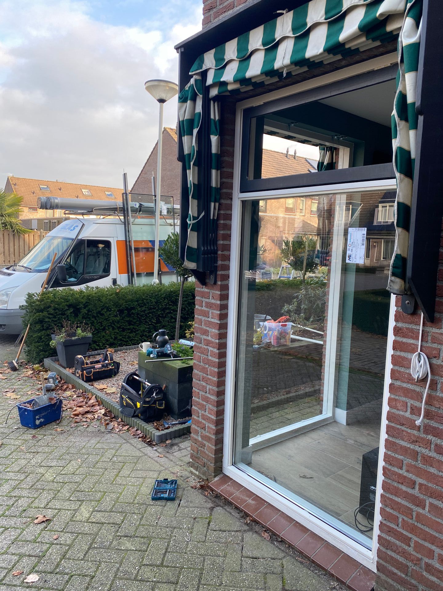 Een bakstenen gebouw met een schuifdeur en een busje ervoor geparkeerd.