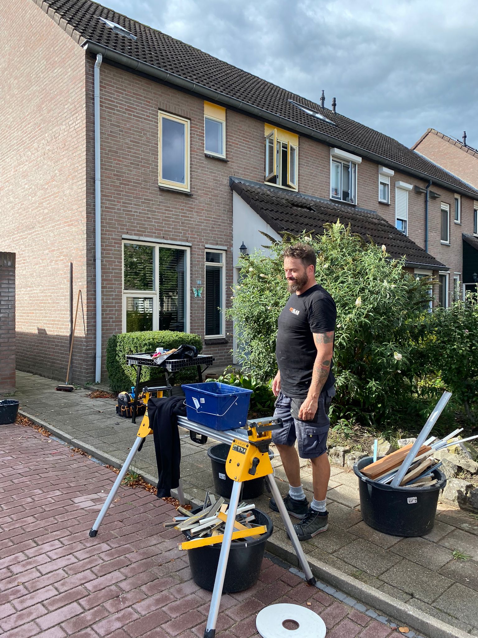 Een man staat voor een huis met een zaag.