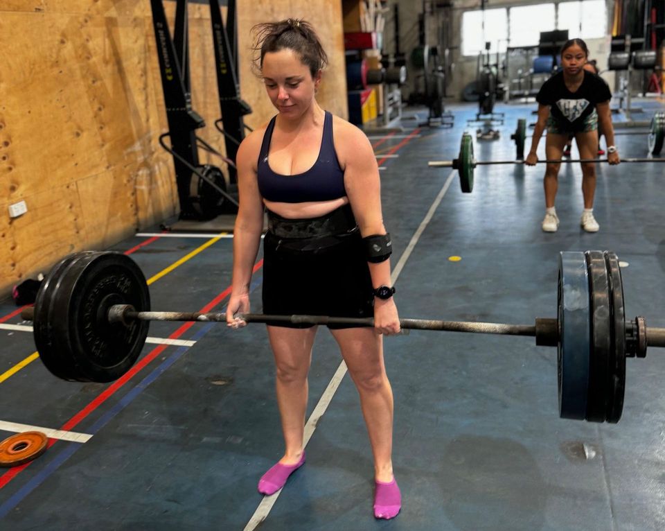 A woman is lifting a barbell in a gym