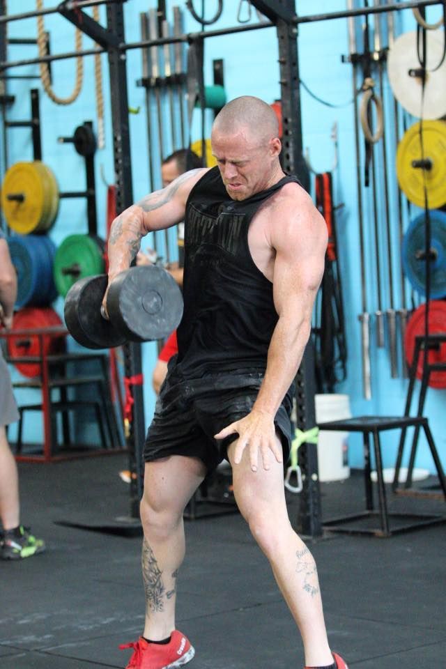 A man is lifting a dumbbell in a gym.