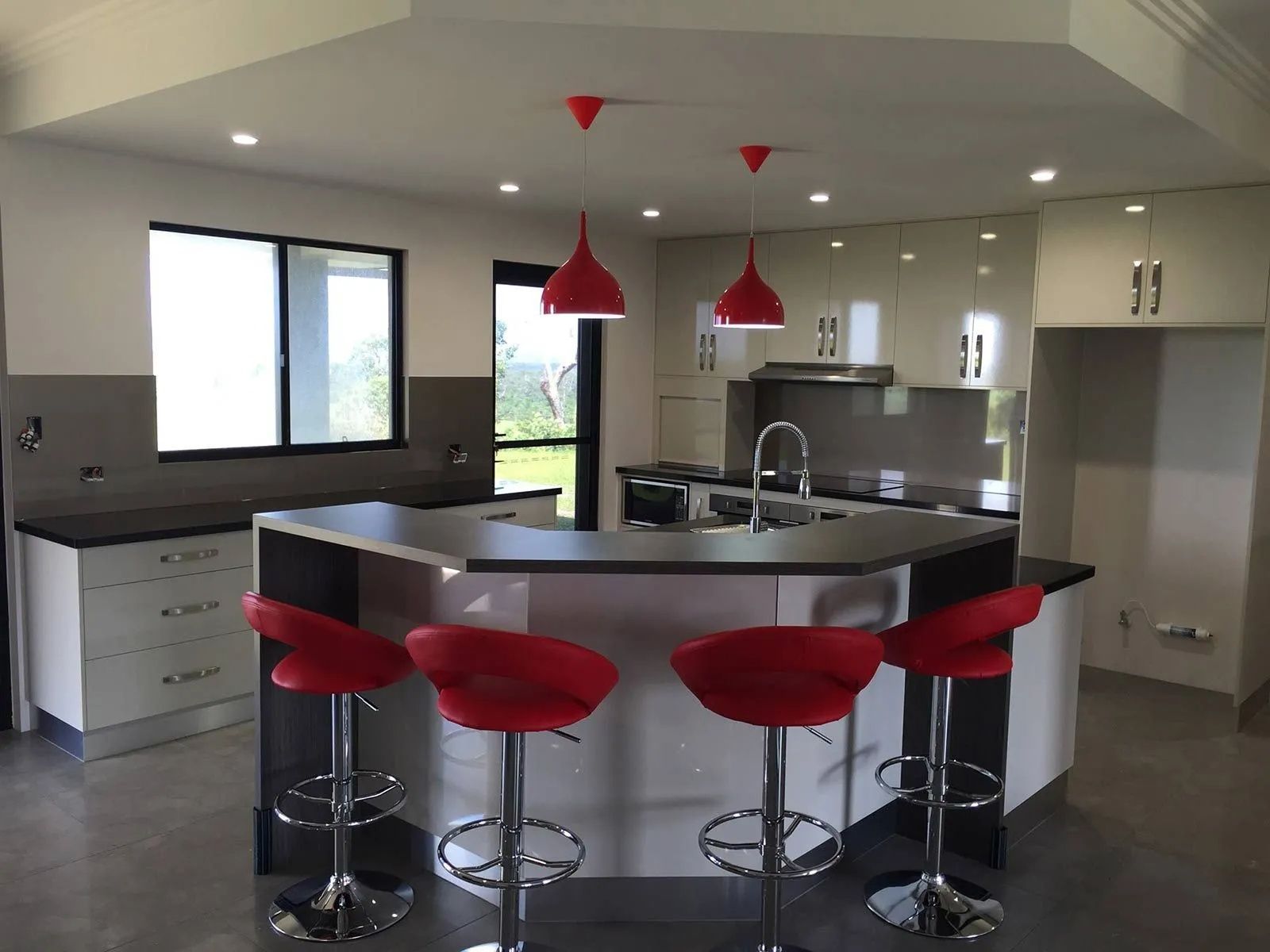 Modern Kitchen With Red Bar Stools and Pendant Lights — Keilbach Kitchens in Cassowary Coast, QLD