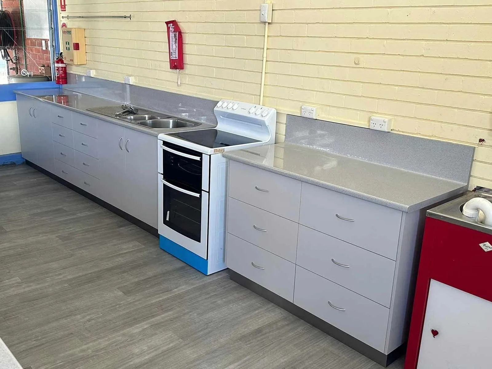 Kitchen With Gray Cabinets, a Stove, Sink, and Countertop Against a Light-colored Wall — Keilbach Kitchens in Innisfail, QLD