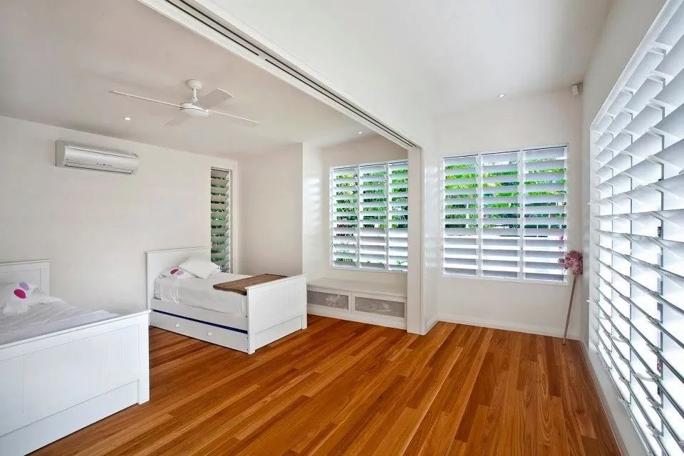 Bedroom With Two White Beds, Wood Floor and White Shutters — Keilbach Kitchens in Garradunga, QLD