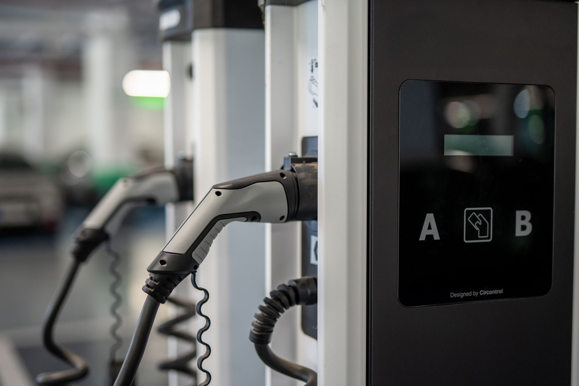 Electric vehicle charging stations with charging cables. Gray and black. 