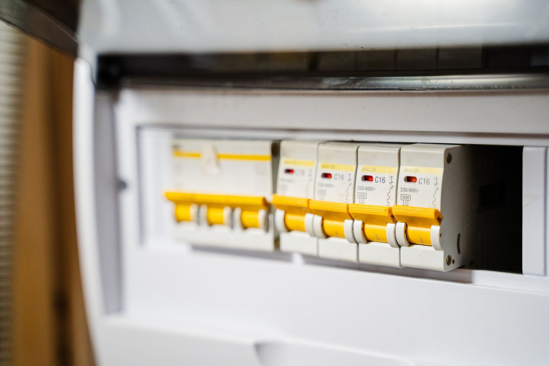 A white electrical breaker panel with several yellow and white circuit breakers, some toggled down.