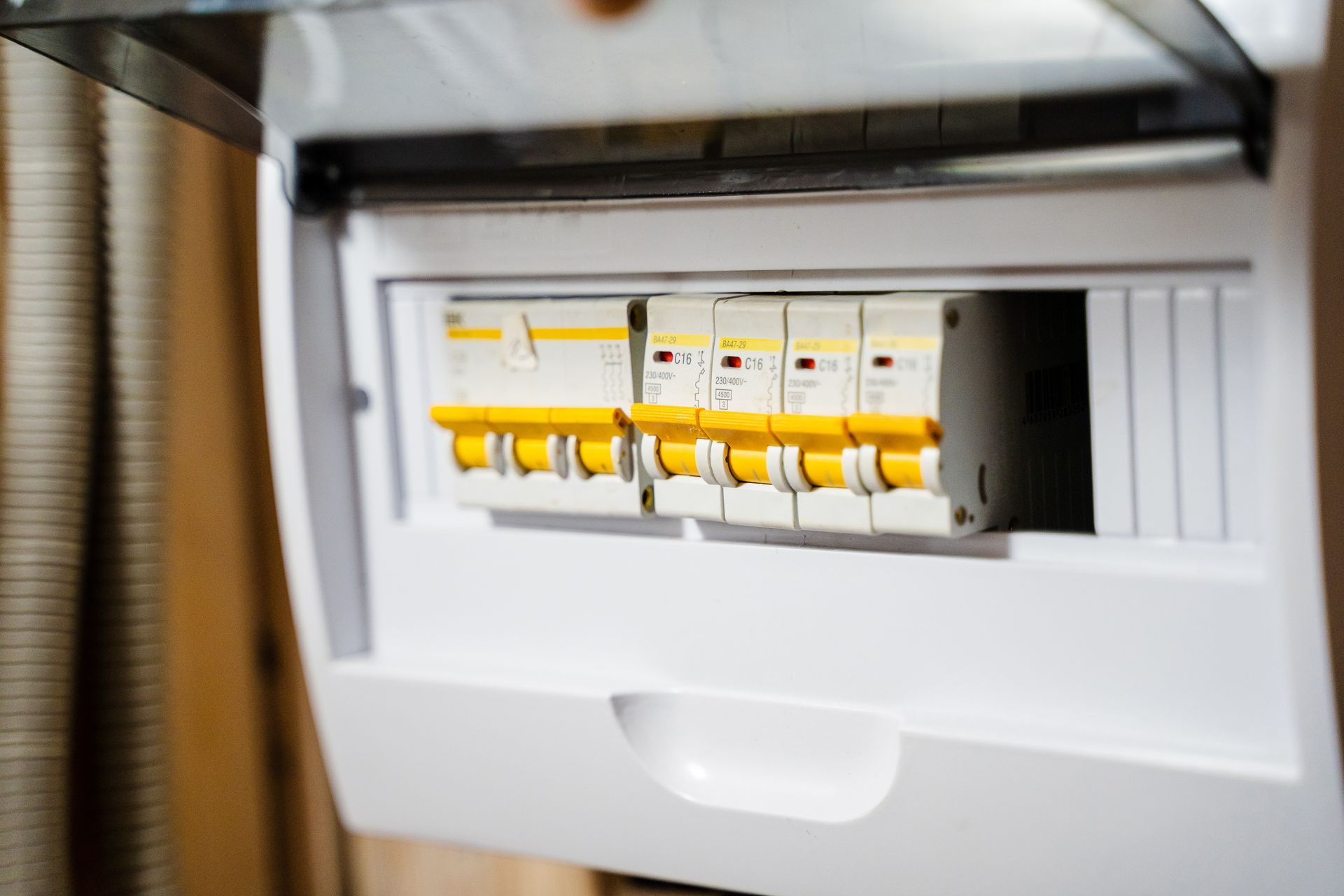 White electrical fuse box with several yellow circuit breakers.