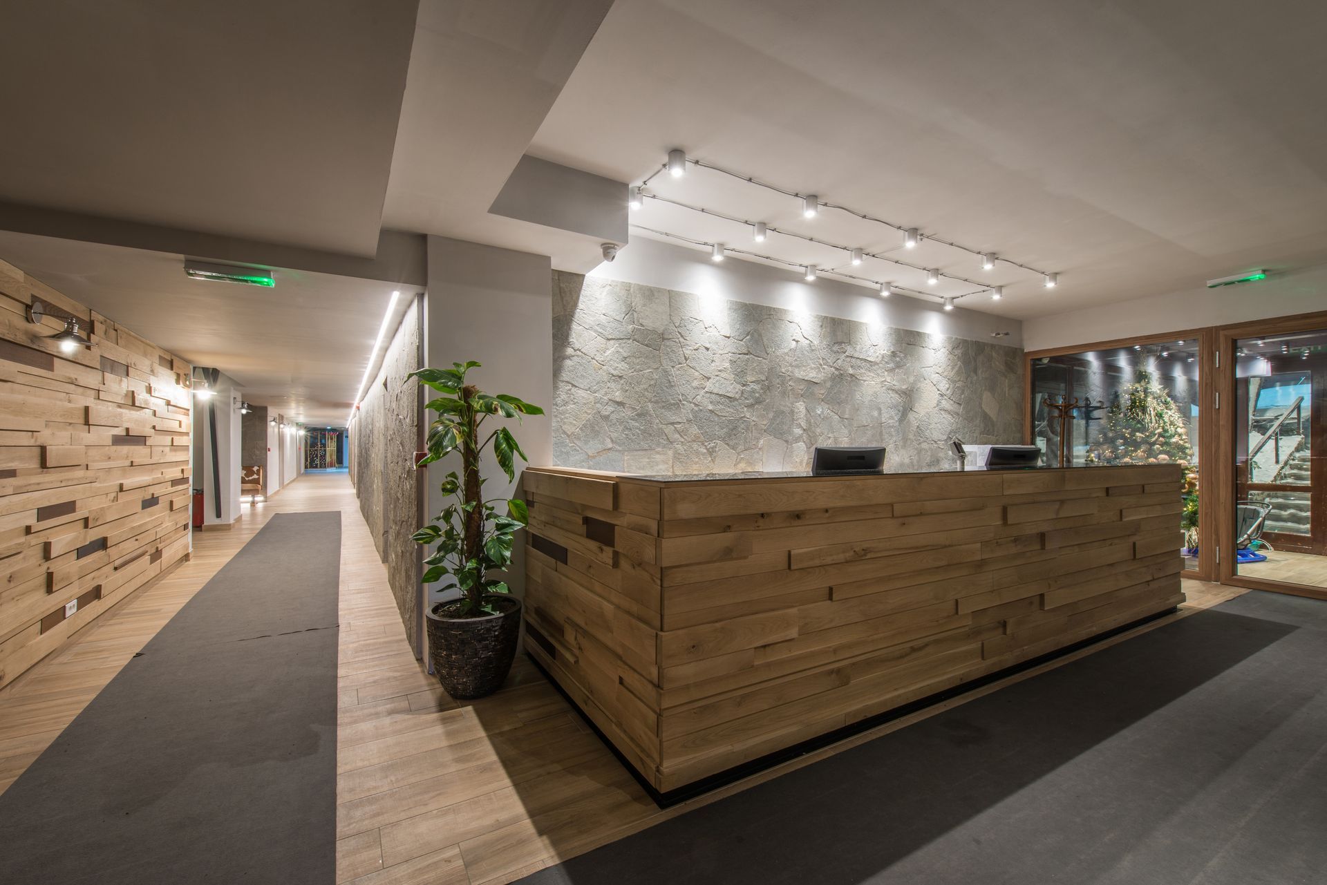 Reception area with wood desk, stone wall, and hallway with wooden paneling.