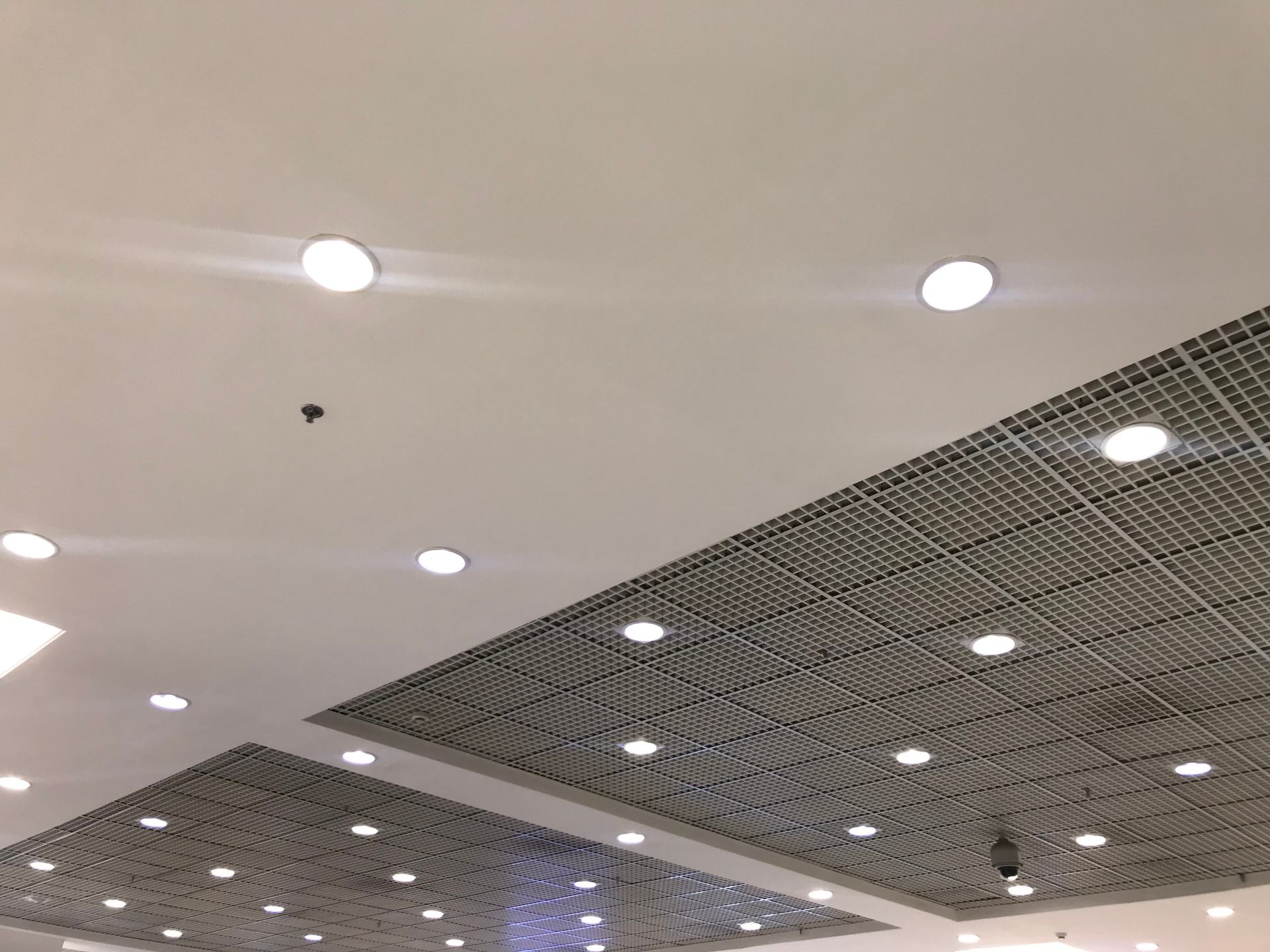 White ceiling with recessed lights, sections of patterned panels.