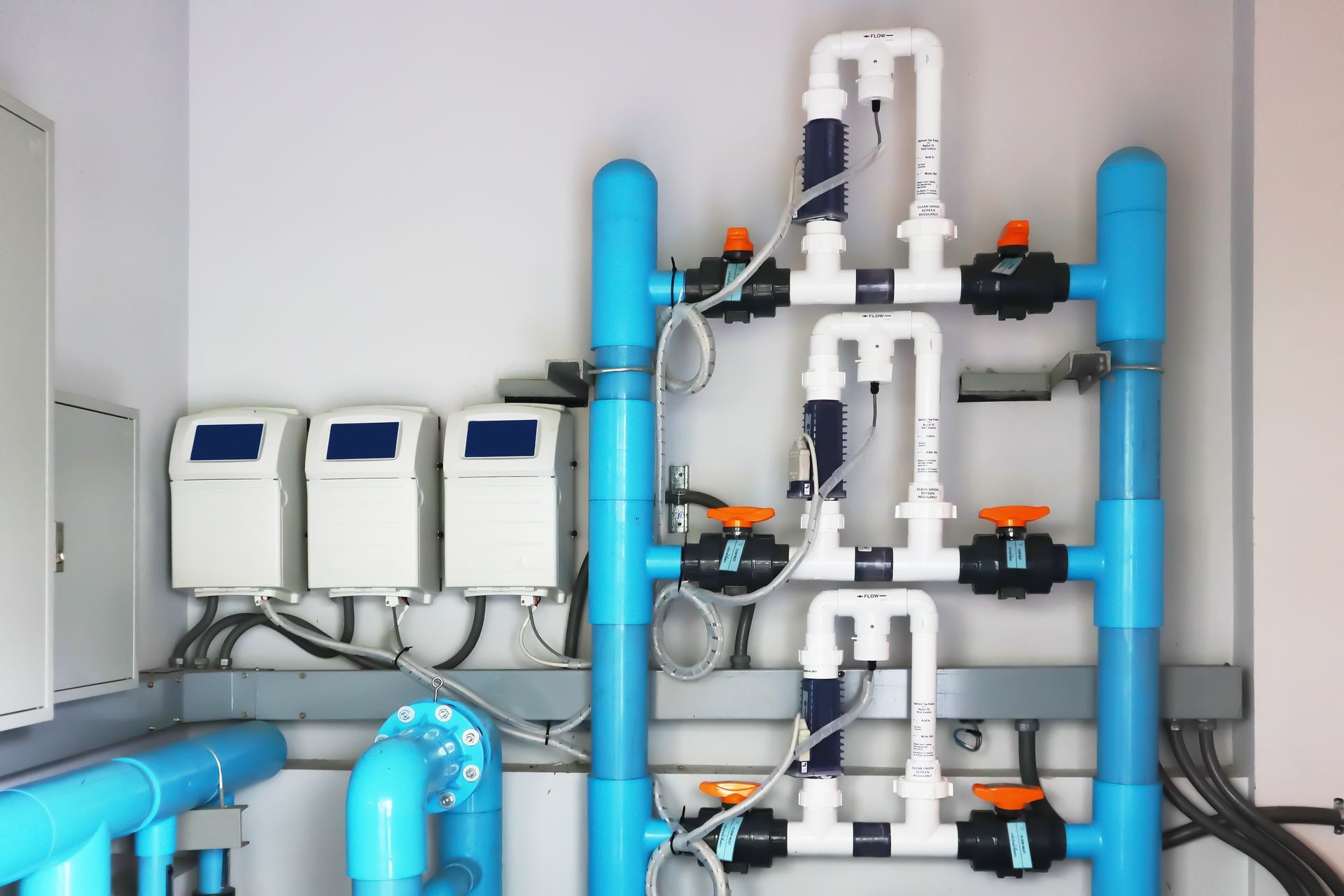 Blue and white pool chemical injection system on a white wall, with electronic control panels.