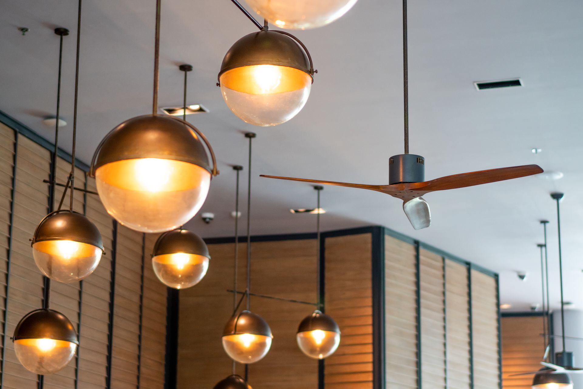 Ceiling lights in a cafe: globe-shaped, brass fixtures with warm, diffused light. A ceiling fan is also present.