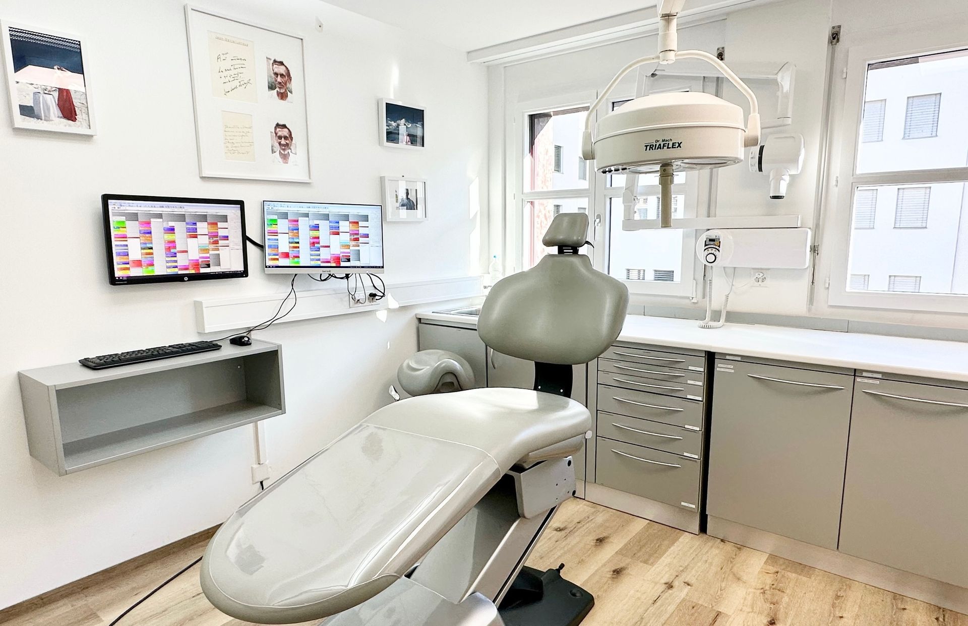 Un cabinet dentaire avec un fauteuil dentaire et deux moniteurs.