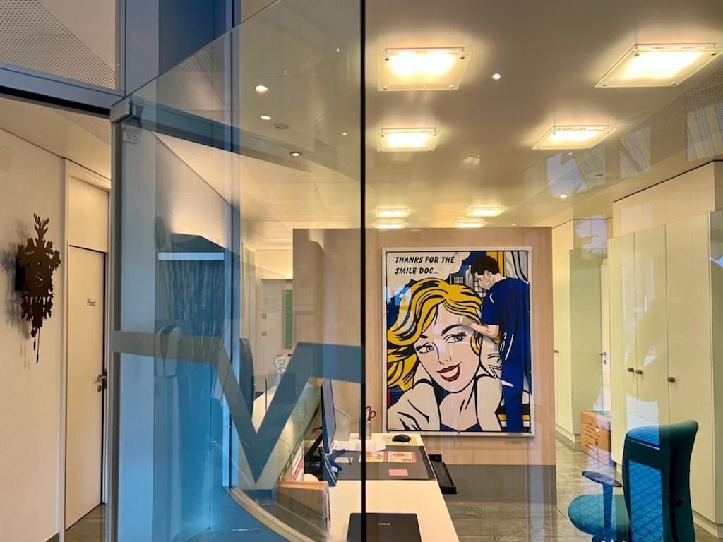 Une pièce avec un tableau représentant une femme sur le mur derrière une porte vitrée.