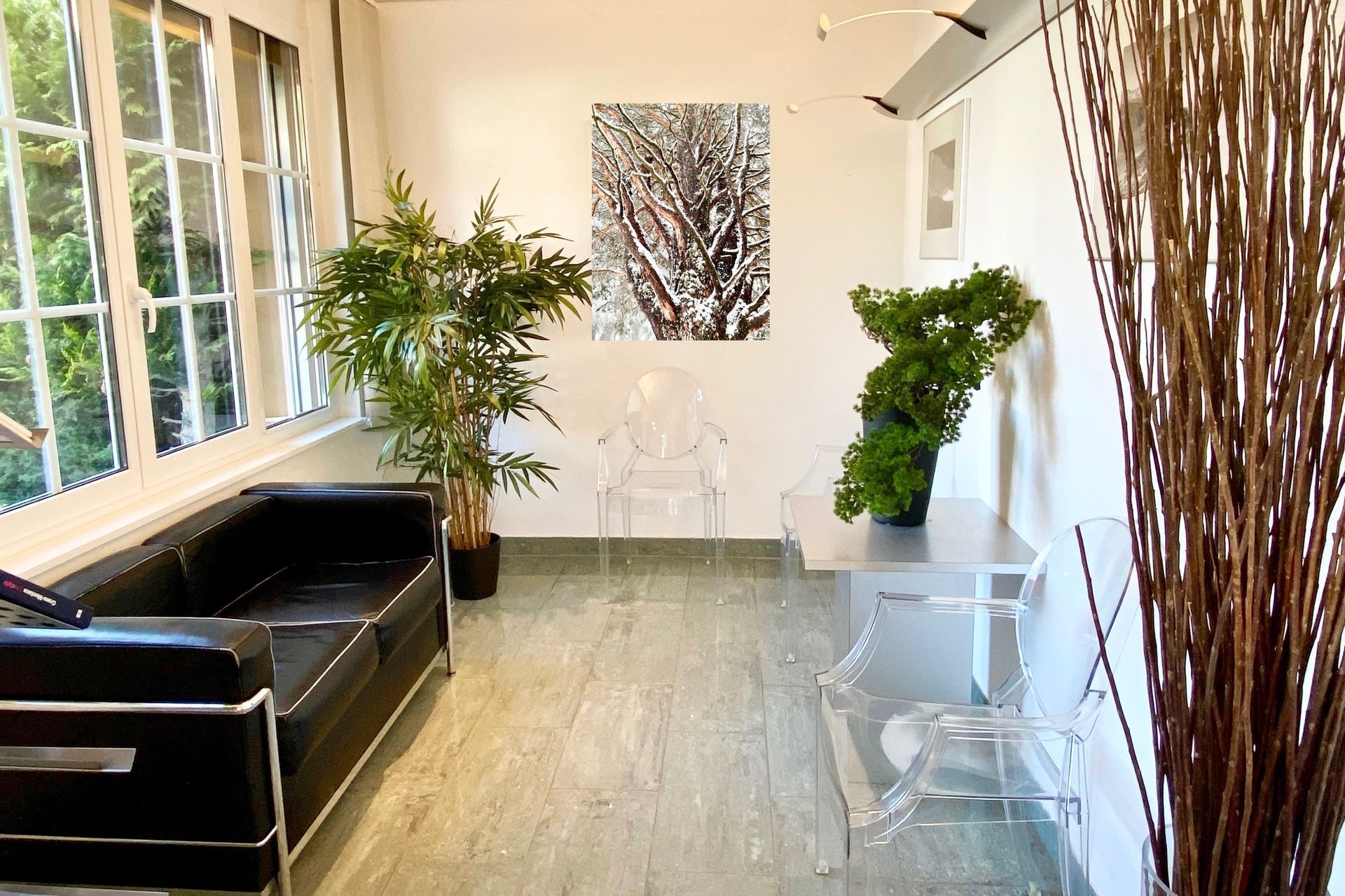 Une salle d'attente avec un canapé noir et des chaises claires