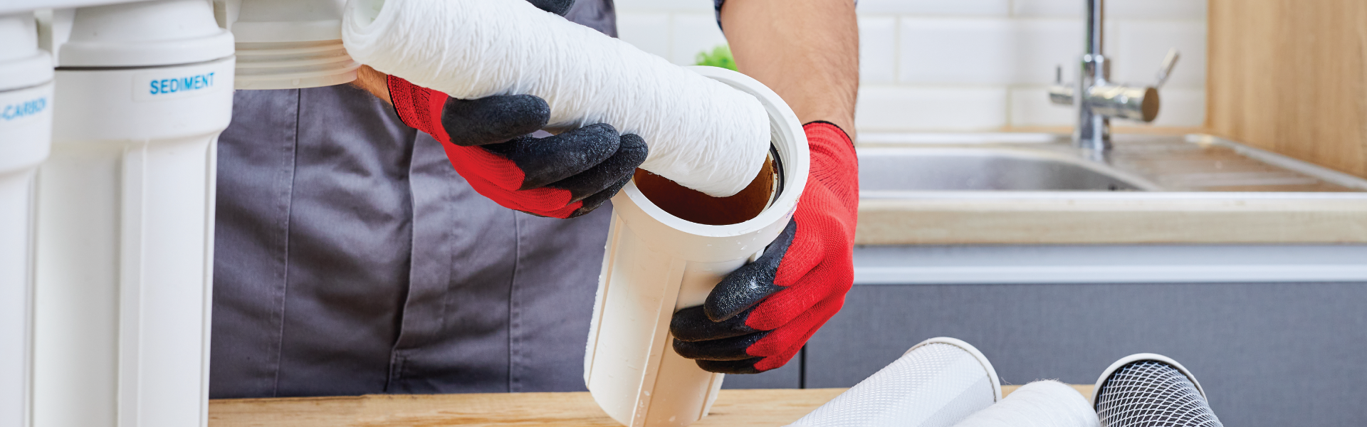 A person is cleaning a water filter in a kitchen.