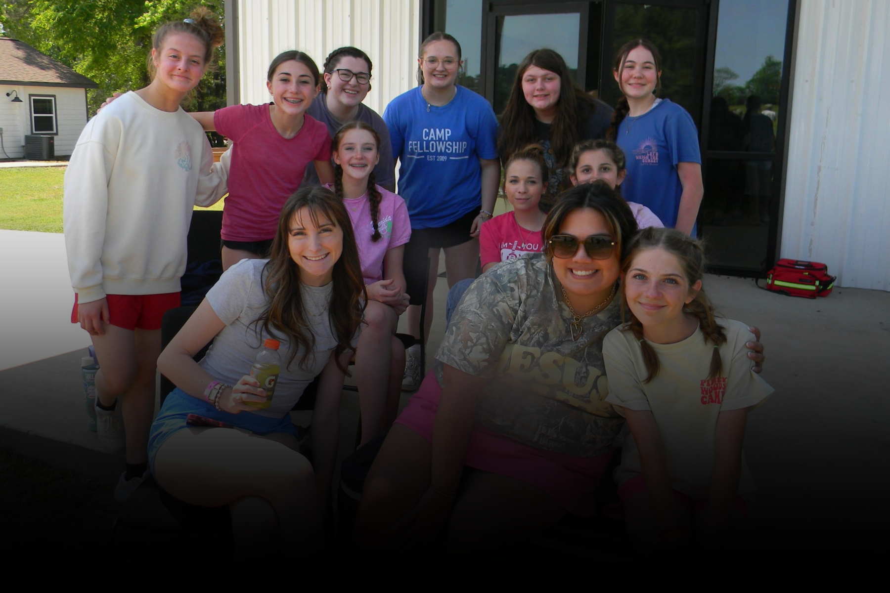 Group of people posing outdoors in front of a building, smiling at the camera.