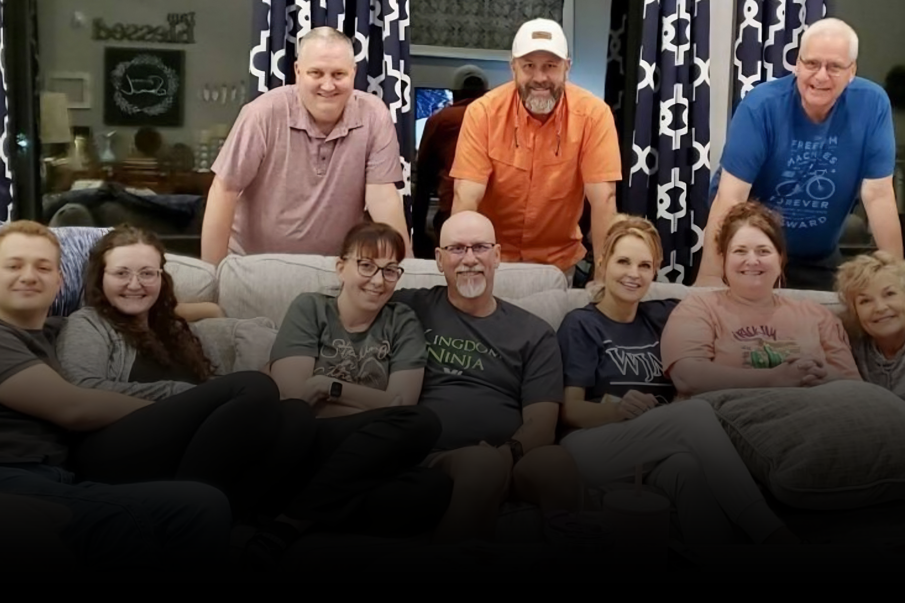 Group of people posing on couches in a living room, smiling at the camera.