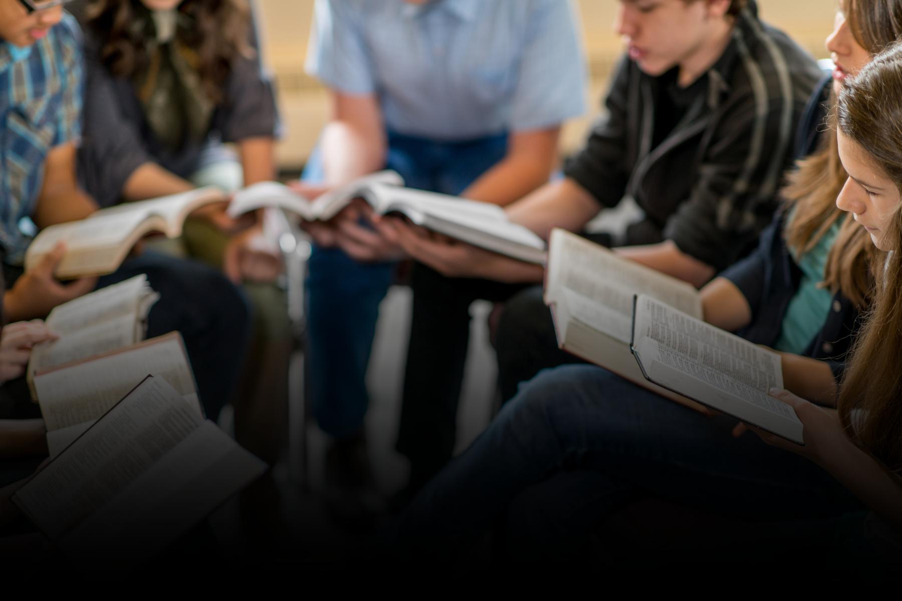Group seated in a circle, reading open books together in a discussion setting.