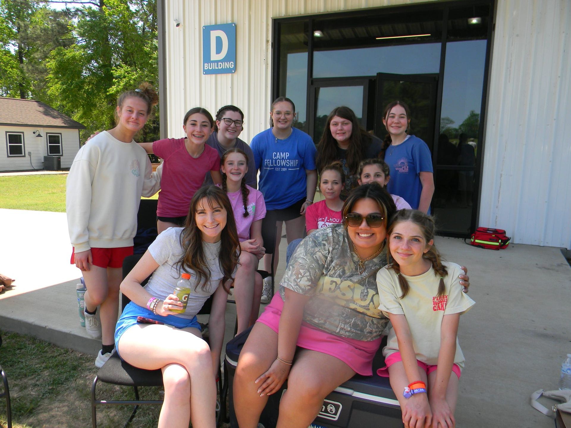 Group of people posing outside a building entrance, smiling and sitting on the steps.