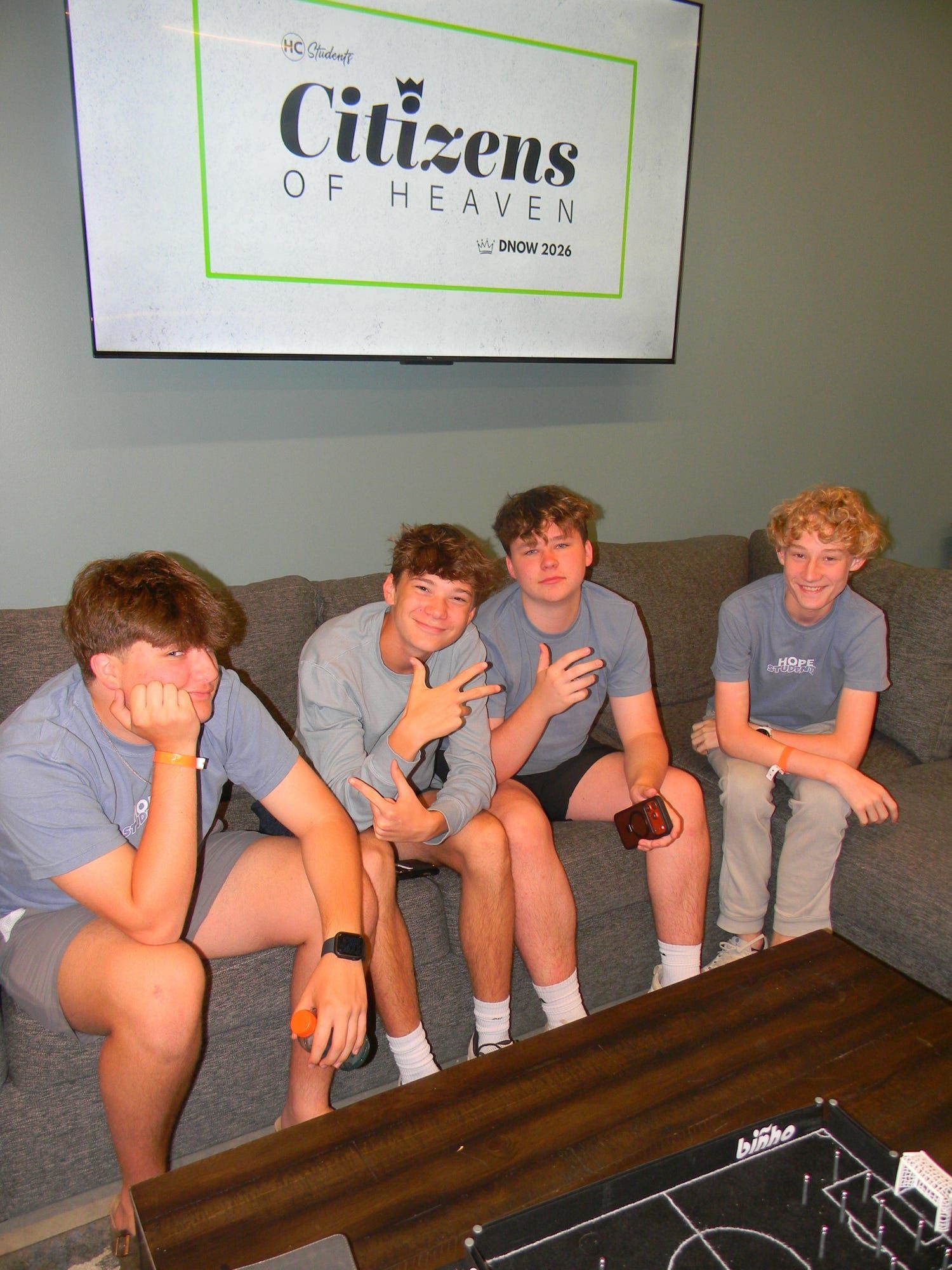 Four teens sitting on a couch in a lounge, with a 