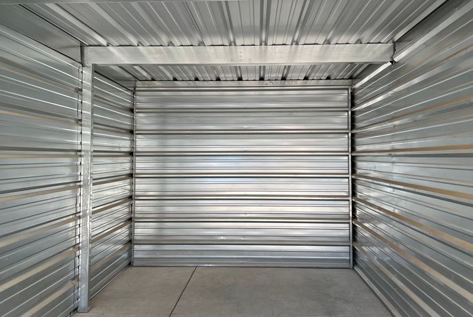 Beautifully clean self-storage unit interior with metal walls and a concrete floor.