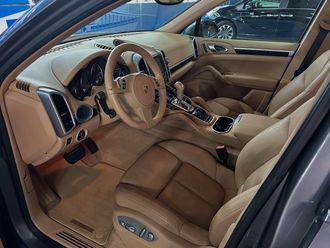 Beige leather car interior with back seats and open door.