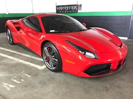 Red Ferrari sports car parked in a parking garage.