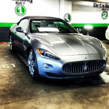 Silver Maserati convertible in a car wash bay.