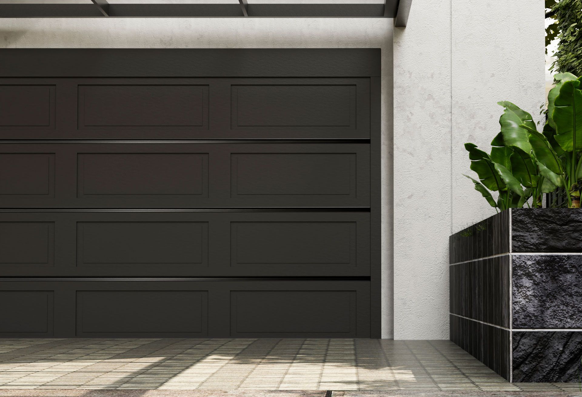 A black garage door is sitting next to a potted plant.