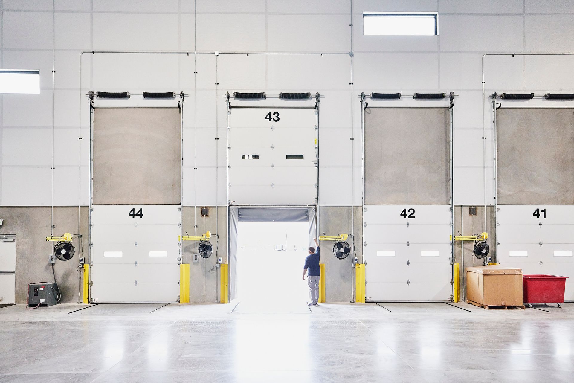 A man is standing in front of a row of white doors with the number 43 on them