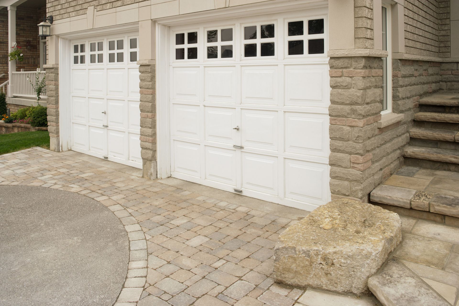A couple of white garage doors on the side of a house.