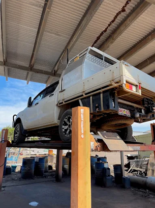 White Pickup Truck On A Lift In A Workshop, Under A Corrugated Iron Roof — KND Autos in Berrimah, NT