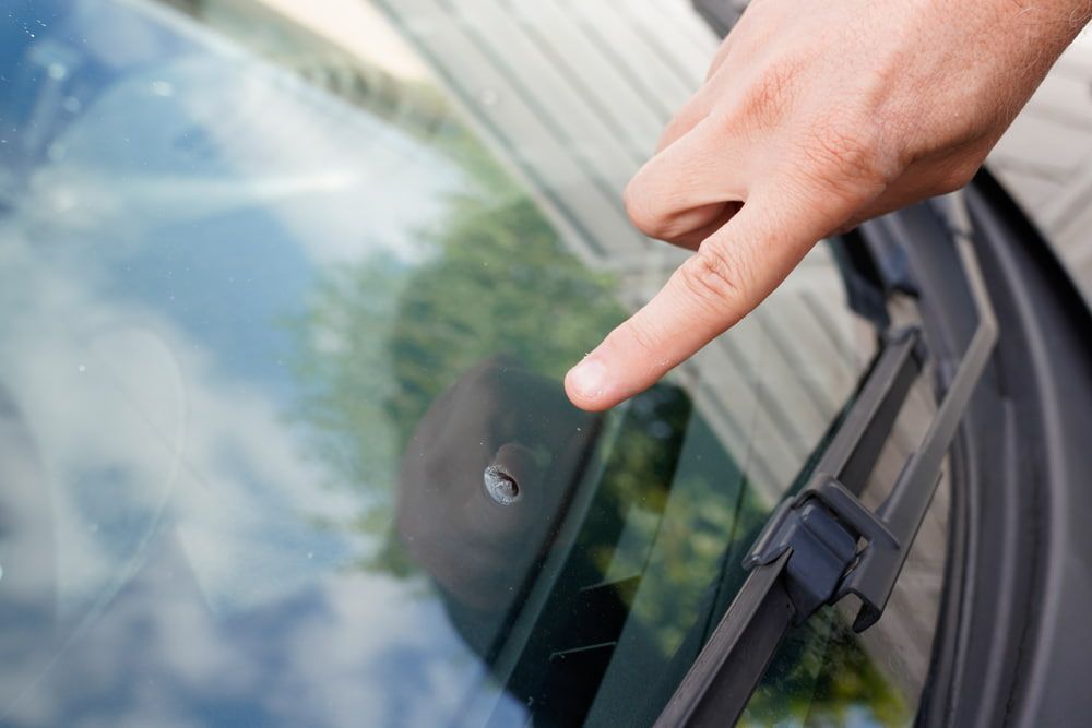 A Person Is Pointing at A Hole in The Windshield of A Car — A1 Windscreens in Quirindi, NSW