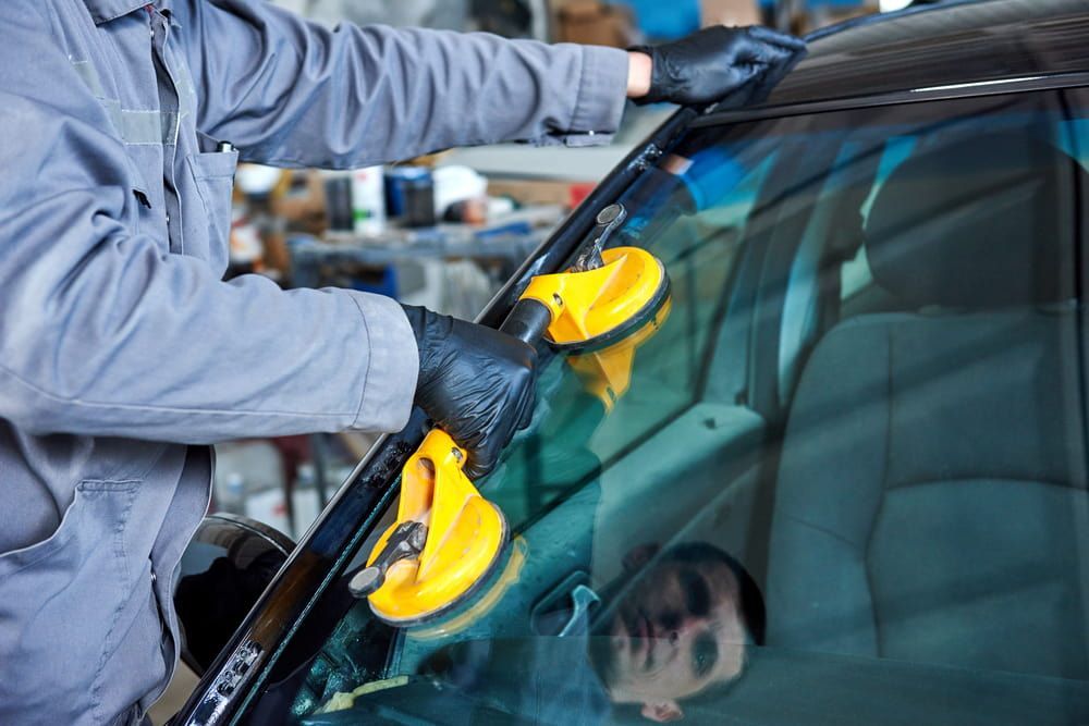A Man Is Installing a Windshield on A Car — A1 Windscreens in Taminda, NSW