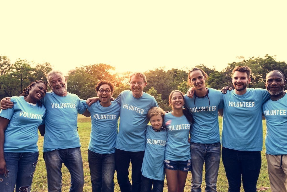 A group of people wearing blue volunteer shirts are posing for a picture.