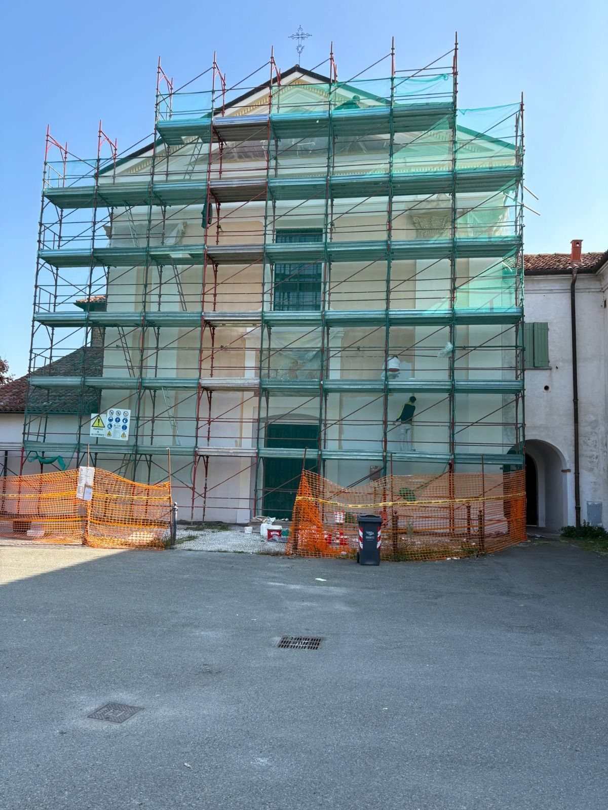 Edificio con impalcature e rete verde in fase di ristrutturazione in un ambiente esterno.