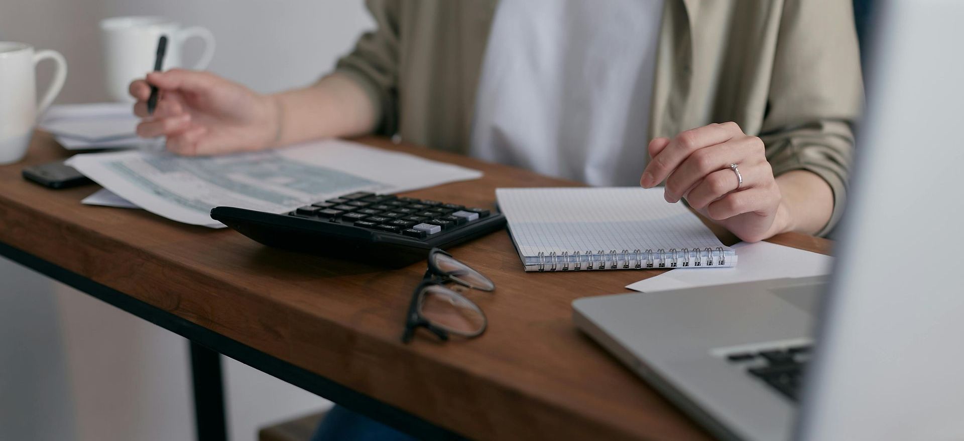 Paper work and bills sitting at desk with pads calculator and laptop